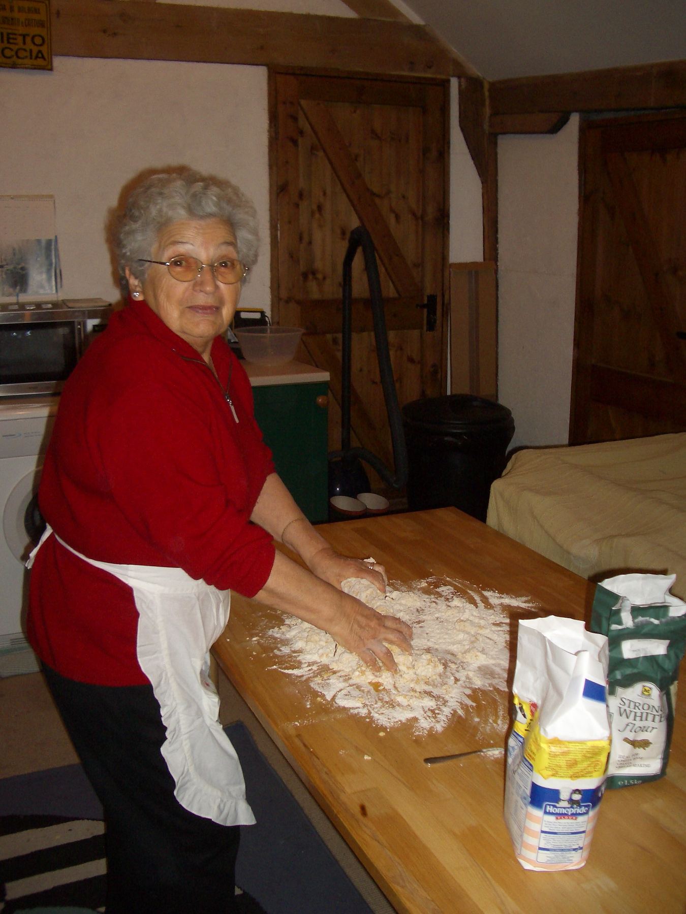 Nonna kneading pasta dough on a wooden table